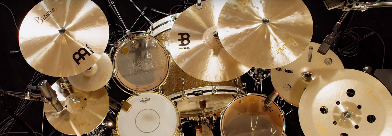 There is a gold drum set with various cymbals that are MEINL branded.