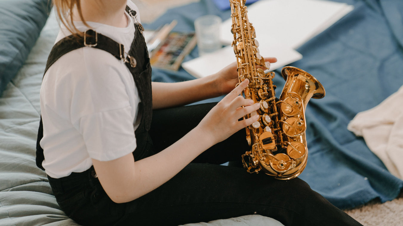Middle school age girl holding an alto saxophone